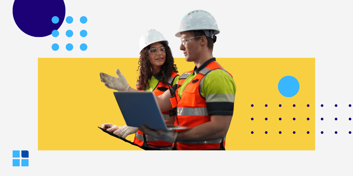 Two quality auditors in hard hats and safety vests use a laptop and clipboard to conduct a layered process audit (LPA) on a factory floor.
