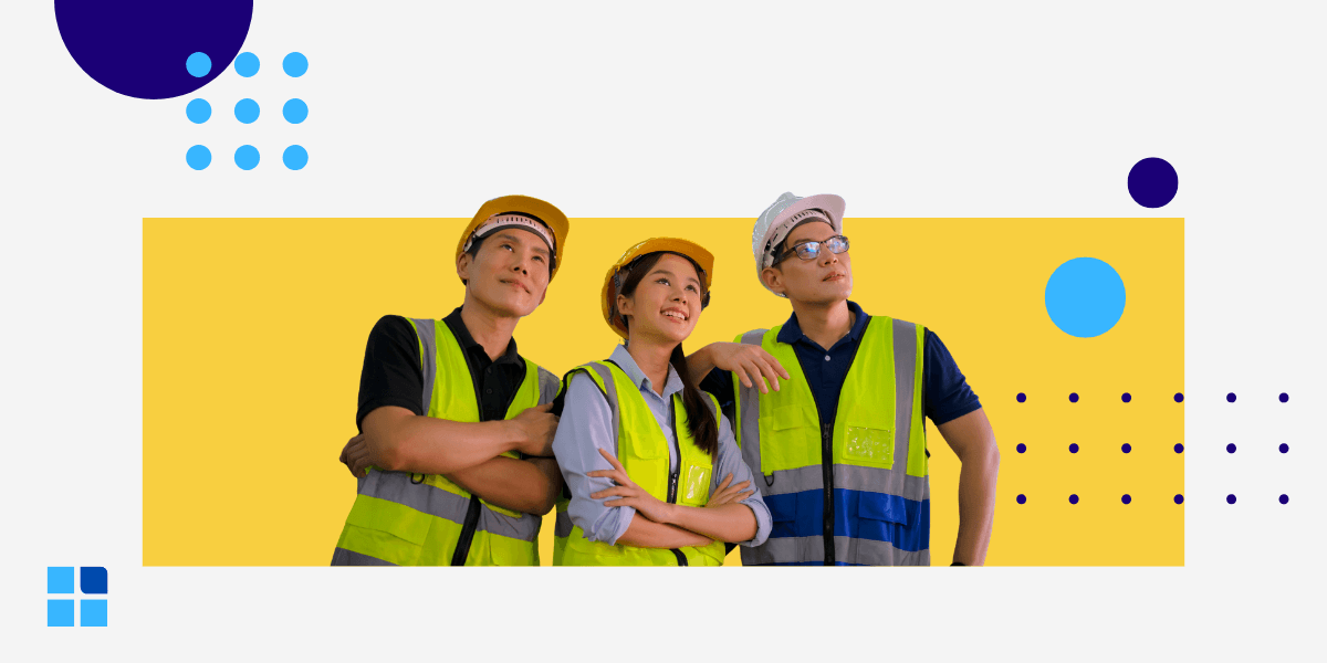 Three diverse industrial workers in hard hats and safety vests stand together, looking up and smiling confidently.