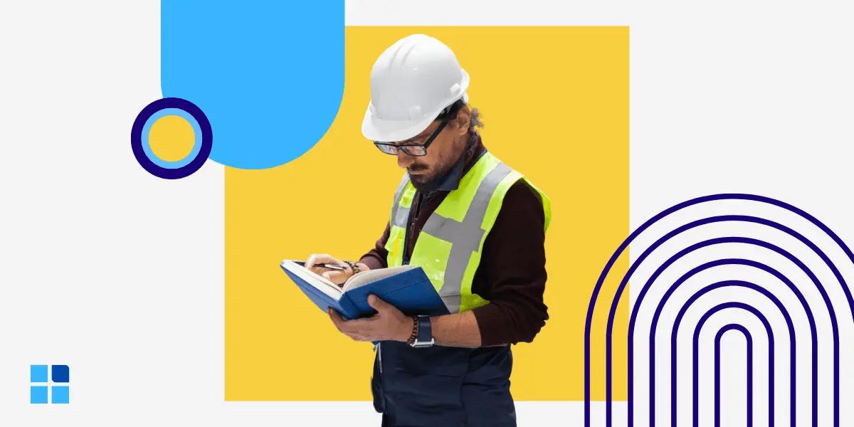 A construction worker in a hard hat and safety vest reads a blue notebook.