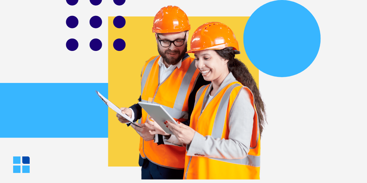 Two smiling construction workers in orange vests and helmets review documents on a tablet.