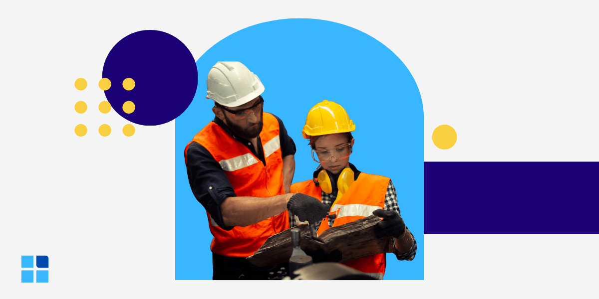 Two industrial workers in orange safety vests and hard hats closely review a logbook, representing the hands-on observation essential to perform an effective Gemba walk.