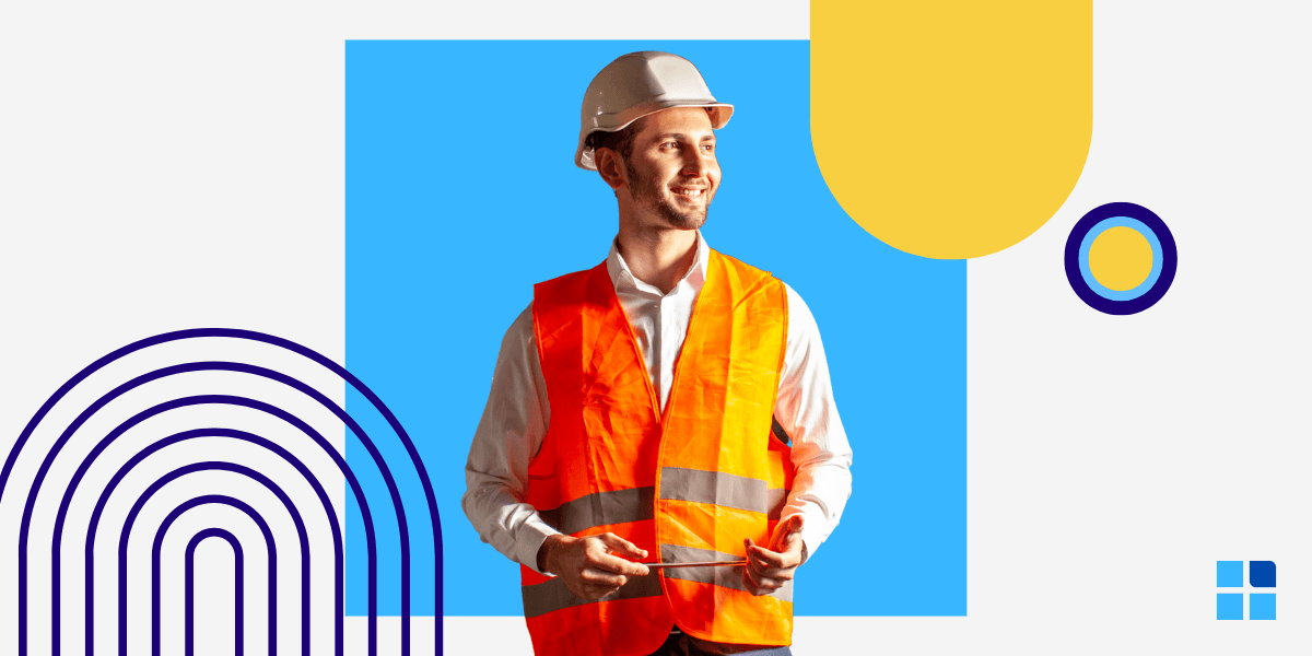 Smiling man in a hard hat and orange safety vest stands confidently, holding a tablet.